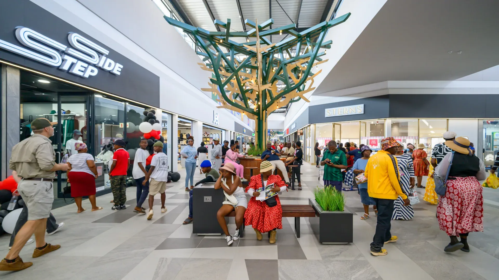 Shoppers in the Malekane Mall concourse under the sculptural tree
