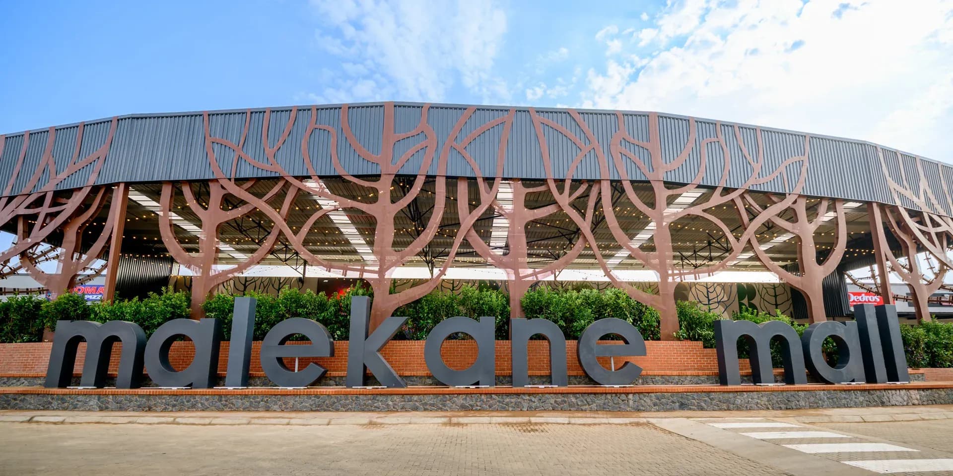 The Malekane Mall wordmark in front of the tree-patterned entrance canopy